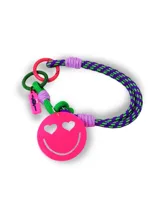 Llavero para bolso con cuerda trenzada en colores violeta y verde, decorado con un dije circular de acrílico rosa con diseño de carita feliz con ojos en forma de corazón. Incluye argollas metálicas de colores y una etiqueta pequeña de silicona.