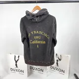 Canguro marrón oscuro con efecto lavado, corte oversize, capucha y estampado en la espalda con la leyenda "San Francisco 1982 California" en color dorado.