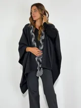 Ruana gris oscuro con detalle de trenzado gris claro y flecos en la parte delantera.