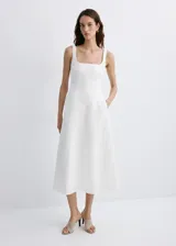Vestido midi color blanco de lino, sin mangas, con escote cuadrado, corte en la cintura y falda evasé con bolsillos laterales.