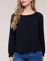 Blusa de modal y elastano color blanco, de silueta holgada, escote redondo amplio con elástico interno fruncido y mangas largas fluidas con puños ajustados.