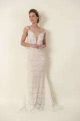 Vestido largo de novia color marfil, de encaje y tul, con apliques bordados y piedras. Tiene escote profundo y falda con cola.