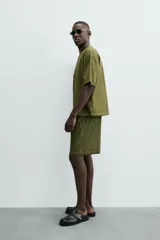 Bermuda de algodón color verde oliva, con corte relajado y textura acanalada vertical. Presenta cintura elástica con cordón interior y bolsillos laterales y trasero.