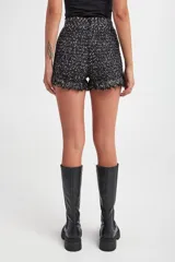 Short negro de tejido de punto con lurex y detalle de flecos en el ruedo.