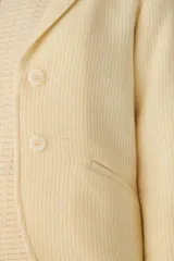 Chaqueta marrón de lana con cuello, solapa y bolsillos ojal. Forro solo en las mangas y terminaciones envivadas. Esquinas redondeadas y mangas con corte en puño que permiten transformarla en manga 3/4. Más larga en la espalda que en la delantera. Abrochadura con dos botones.