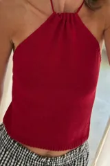 Top tejido color rojo, de punto fino, con cuello halter fruncido y tirantes finos.