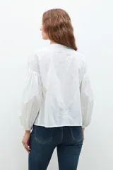 Blusa blanca de manga larga con escote en V y bordados en el frente.
