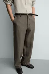 Pantalón straight fit color verde militar, confeccionado en lino, con cintura con trabillas, cierre frontal con cremallera y botón, y bolsillos laterales.