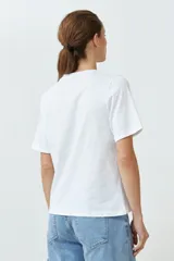 Remera blanca de algodón con cuello redondo y apliques circulares plateados.