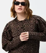 Cardigan de punto con estampado animal print, cuello redondo y cierre frontal con botones. Presenta mangas largas abullonadas con puños ajustados y un corte corto.
