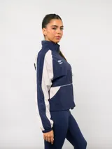 Campera deportiva Umbro del Club Nacional de Football, con diseño de bloques de color en azul marino y blanco. Presenta cuello alto, cierre frontal completo, bolsillos laterales y el escudo del club junto al logo de la marca en el pecho.