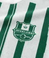 Remera de punto manga corta con diseño rayado vertical en color verde y blanco. Presenta cuello redondo, sisa desplazada y detalles gráficos tipo jersey de fútbol con el número 10 y el logo de la marca Reckless en el frente.