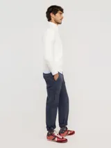 Sweater de punto acanalado en color azul marino, con cuello alto y cierre frontal parcial. Presenta mangas largas con puños acanalados y un pequeño logo bordado en rojo en el pecho.
