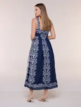 Vestido midi azul marino con bordados florales blancos, escote cuadrado, breteles anchos y falda amplia con bolsillos.