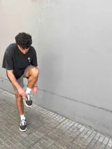 Camiseta de corte oversize color negro con efecto lavado, manga corta y cuello redondo. Presenta un estampado gráfico en la espalda con dos palmeras, una hamaca y un ángel, junto con la inscripción 'Paradise Holiday' y el logo de la marca.