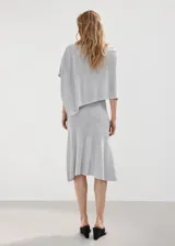 Falda midi evasé de tejido de punto fino color gris, con diseño semitransparente, tiro medio y sin cierre.