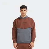 Canguro oversize de felpa con capucha, combinado en color marrón y gris, con bolsillo tipo canguro y pequeño estampado frontal.