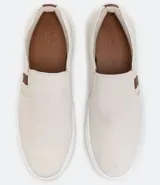 Championes tipo slip on marca Viko, de color negro con suela de goma blanca. Presenta un diseño minimalista sin cordones con paneles elásticos laterales y un pequeño detalle de etiqueta en color marrón.