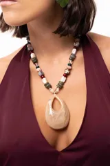 Collar corto con un gran dije central en forma de gota de acrílico marmolado en tonos beige. La cadena está compuesta por una variedad de cuentas de acrílico, piedras naturales y cristales checos en una paleta de colores tierra, verde y granate.