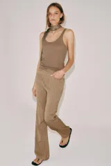 Pantalón flare de tiro medio, confeccionado en mezcla de viscosa y lino, con diseño de rayas verticales en tono beige. Cuenta con bolsillos delanteros y bajo acabado en línea evasé. Cierre frontal con cremallera, botón y ganchos metálicos.