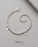Pulsera de plata elaborada con cuentas esféricas texturizadas y dos dijes colgantes en forma de estrella.