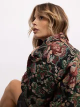 Campera tipo bomber con estampado floral estilo tapicería en tonos oscuros, con cuello clásico, cierre frontal con botones metálicos y bolsillos laterales.