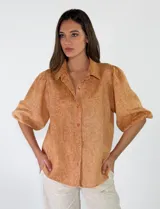 Camisa de lino color beige, con mangas abullonadas tres cuartos y cierre frontal de botones.