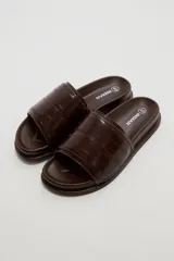 Sandalias planas color marfil, con tira ancha acolchada en el empeine y suela baja con borde oscuro.