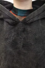 Canguro con capucha de calce holgado, confeccionado en tejido con efecto lavado ácido en color gris oscuro. Presenta un bordado tonal en el centro del pecho y un bolsillo frontal tipo canguro.
