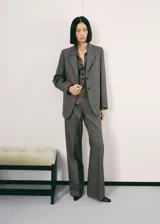 Blazer de corte recto confeccionado en tejido de mezcla de lana jaspeada. Presenta cuello con solapas de muesca, cierre frontal con botones, mangas largas con puños abotonados, dos bolsillos de parche frontales y abertura posterior en el bajo. Incluye forro interior.