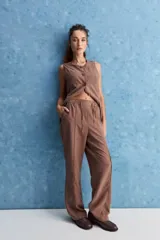 Pantalón de corte recto y holgado, color marrón, con costuras frontales verticales que estilizan la silueta.