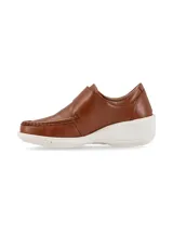 Zapato tipo slip on color camel, confeccionado en cuero con textura granulada. Presenta un diseño de mocasín con costuras reforzadas en la puntera, ajuste mediante una solapa con velcro y una suela de plataforma blanca de goma.