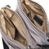 Bandolera mini color gris claro, de formato compacto rectangular. Cuenta con doble compartimento con cierre superior, correa larga regulable negra y herrajes metálicos color níquel. Tiene un bolsillo interno y un logo circular en el frente con la inscripción "Extra Large".