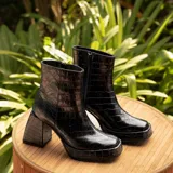 Botas cortas negras de cuero vacuno con textura tipo cocodrilo. Taco de madera forrado en cuero de 8cm, entre suela de goma de 2cm forrada en cuero, inclinación de horma de 6cm y caña de 15cm. Cierre YKK del lado interno y horma de punta cuadrada.