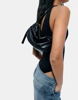 Bolso tipo hobo de cuero sintético negro, con efecto arrugado o fruncido en la parte superior y cierre de cremallera plateada. Posee una correa de hombro ajustable.
