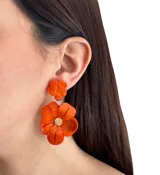 Aros colgantes con forma de flor hechos de resina color azul. Se ajustan con perforación y no contienen níquel.