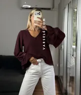 Blusa de tela cey color bordó, con escote en V y mangas largas abullonadas que terminan en puños con detalle de encaje y volados.