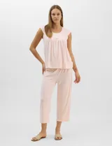 Pijama compuesto por remera sin mangas con escote redondo, botones frontales y detalle de puntilla, acompañado de un pantalón capri con cintura elástica. Presenta un estampado floral en tonos rosados sobre base gris.