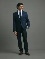 Saco de vestir azul marino con cuello solapa, manga larga y cierre frontal de dos botones. Presenta un diseño clásico con bolsillos laterales con solapa y un bolsillo superior en el pecho.