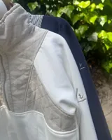 Buzo de algodón combinado en azul marino, con cuello alto, medio cierre frontal y un panel superior capitoneado con diseño a rayas.