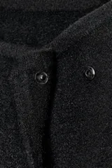 Chaqueta estilo bomber de punto color negro, con cuello subido, manga larga y cierre frontal cruzado con botones ocultos a presión. Presenta bolsillos delanteros de vivo.