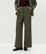 Pantalón de sastrería modelo wide leg color verde militar, confeccionado en crepé. Presenta pliegues delanteros, cintura con trabillas e incluye un cinturón de gamuza a tono.