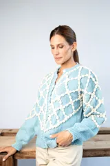 Cárdigan celeste de lana merino con diseño calado en color crudo y botones de nácar.