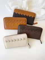 Billetera grande de cuero color negro y camel, con cierre metálico y detalle de costuras cruzadas en la parte superior. Incluye monedero interno.