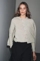 Chaqueta de lana 100% color gris claro, con cuello redondo, manga larga y cierre frontal con botones.