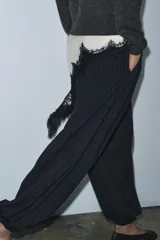 Pantalón de tiro medio, color negro con rayas diplomáticas finas blancas. Cintura elástica ajustable con cordones y bajo abullonado con elástico.