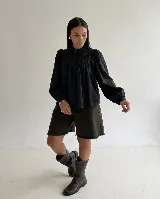 Camisa blanca de algodón con cuello mao, mangas largas con puños elásticos y cierre frontal de botones. Presenta un diseño con pliegues frontales y detalles bordados en la parte superior del pecho.