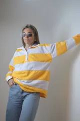 Sweater de punto a rayas horizontales amarillas y blancas, con cuello polo y mangas largas.