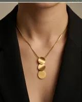 Collar de acero con baño de oro, compuesto por una cadena tipo serpiente y un dije vertical formado por tres discos circulares de acabado cepillado.