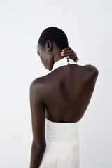 Top negro sin mangas con cuello halter drapeado y cierre posterior con botón.